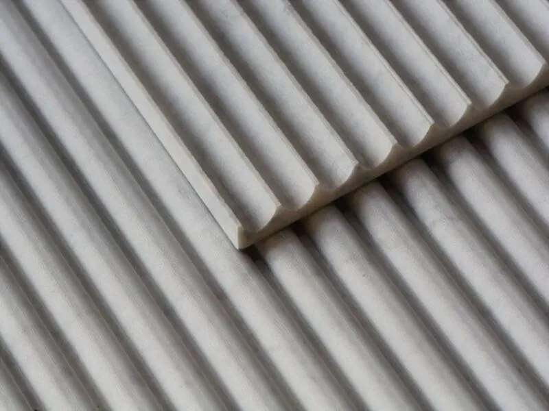 Close-up view of marble tiles with alternating concave and convex fluted profiles arranged in parallel, highlighting textured grooves and three-dimensional surface design.