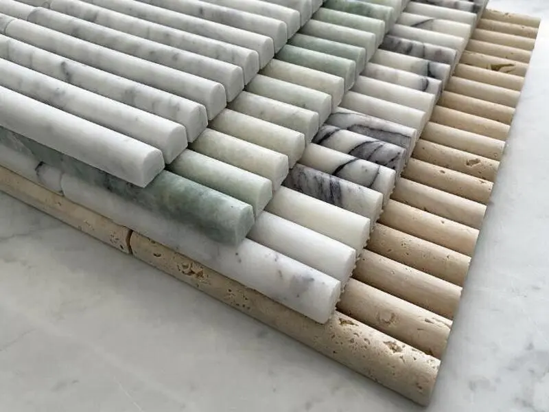 Close-up of multi-colored convex fluted stone tiles, including white, green, beige, and grey varieties, arranged in parallel rows to showcase three-dimensional texture and diverse natural stone patterns.