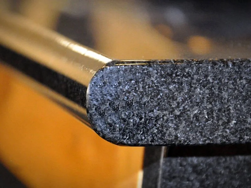 Close-up detail of full bullnose granite edge profile on polished countertop highlighting smooth rounded stone finish.